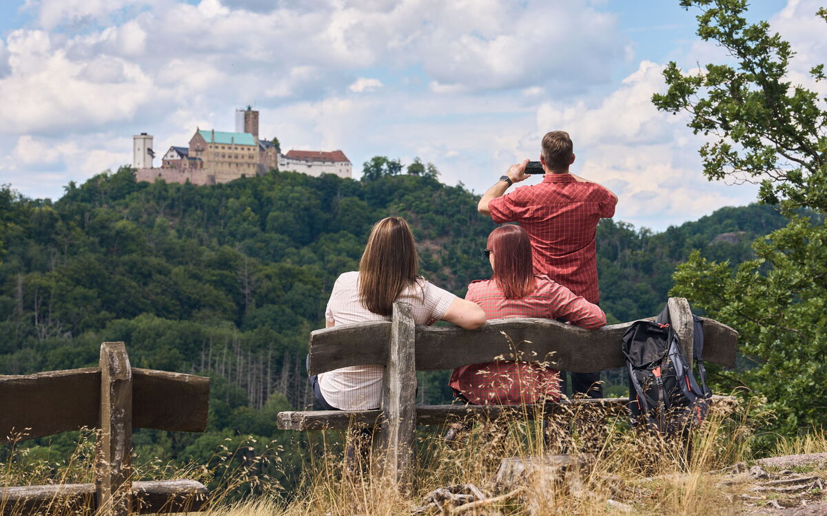 Drei Wanderer genießen den Ausblick vom Breitengescheid bei Eisenach zur Wartburg